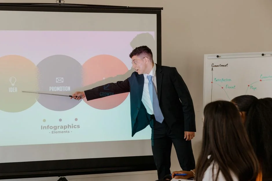 Two colleagues in a meeting room discussing financial charts and graphs on a laptop and paper.